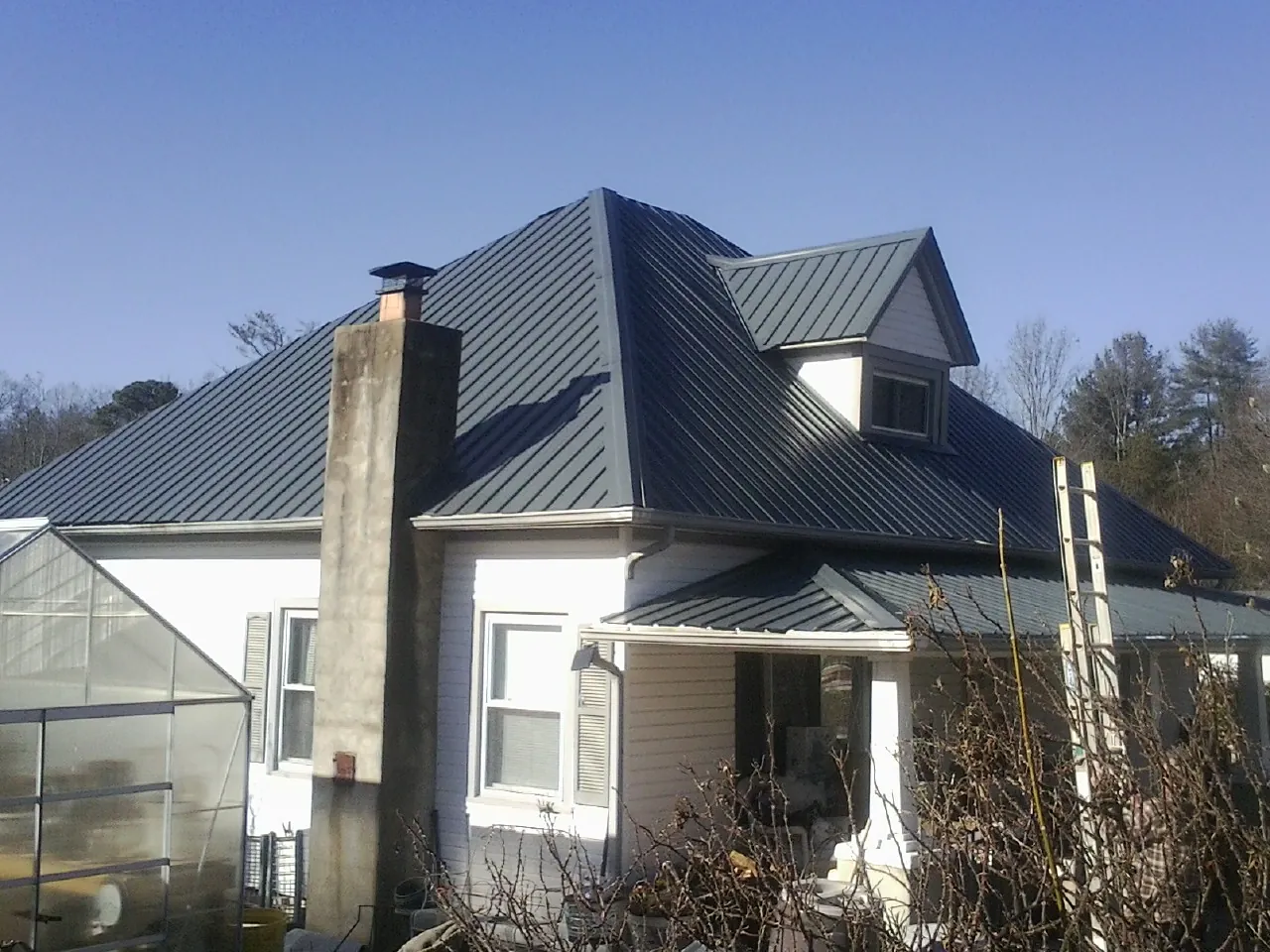 Dark blue standing seam metal roof on a white farmhouse with dormer — Slate & Tile Roof Repair by Roofing Brothers in Kimballton