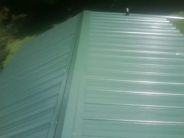 New green metal panels meeting at the ridge of a roof — Flat Roof Repair work by our crew in Kimballton