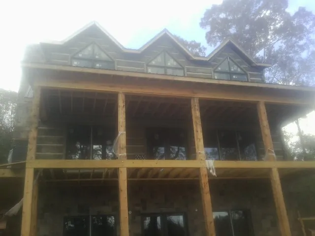 Dormers and porch framing on a large log home under construction — Roof Coating work by our crew in Kimballton