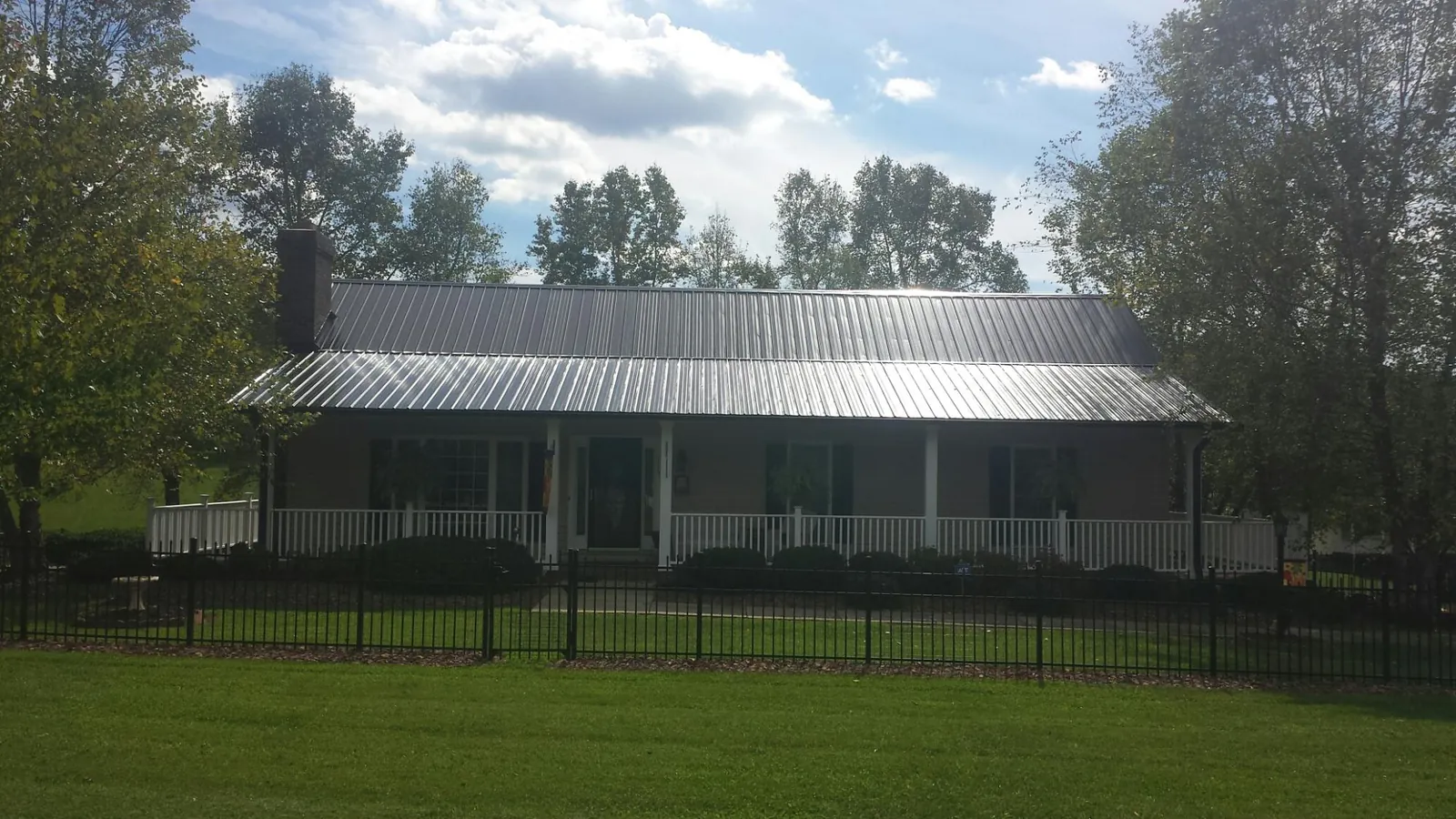 Gray metal roof on a brick ranch with a full width front porch — Gutter Guard Installation work by our crew in Kimballton