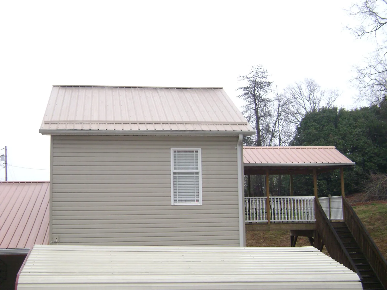 Tan metal roofs on a two story addition and attached porch, from a Roof Replacement job in Kimballton